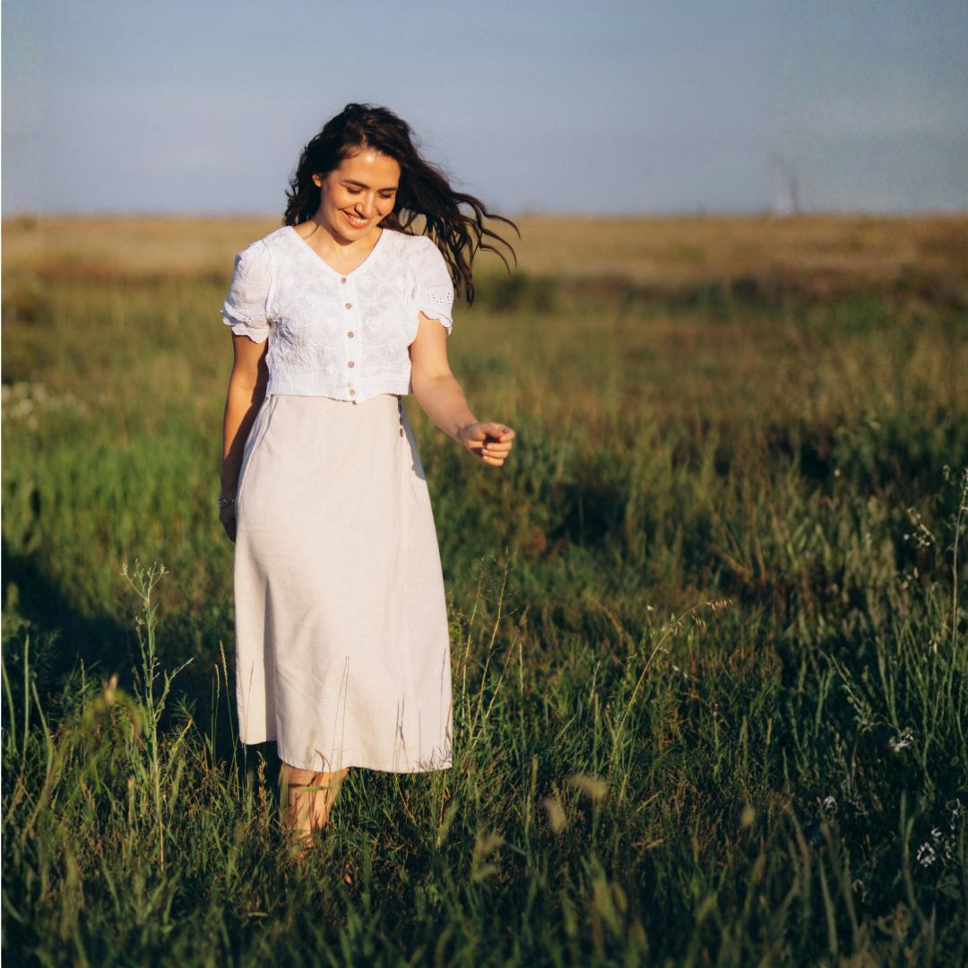 Woman walking peacefully through a grassy field, illustrating the truth that God will carry you during difficult seasons.